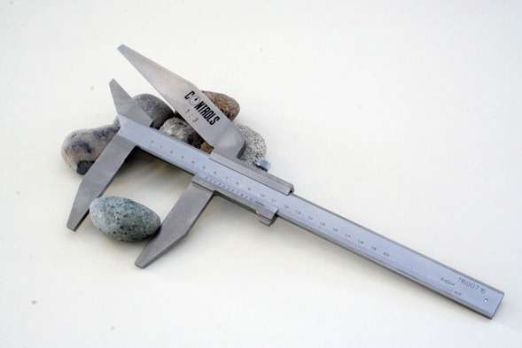 Aggregate samples being measured for shape index — physical properties such as Mohs hardness, density, abrasion index and Bond Work Index together define how a rock will behave in a crushing plant